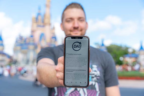 Man holding up his phone on the DAS screen in front of Disney World's Cinderella Castle.