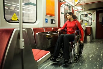 Woman in wheelchair rides subway train.