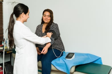 A woman getting her blood pressure taken by a doctor.