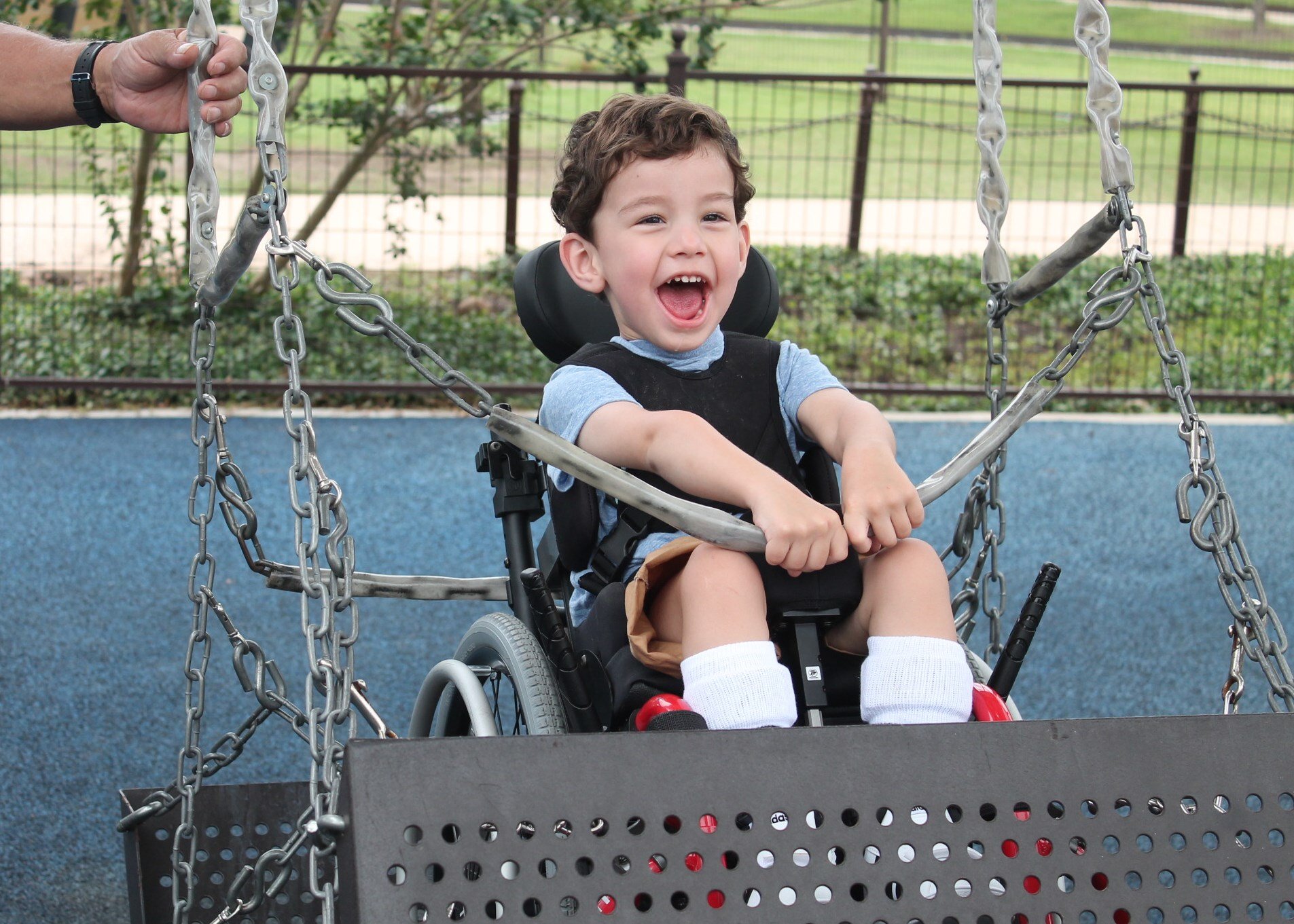 Little boy on wheelchair swing laughing.