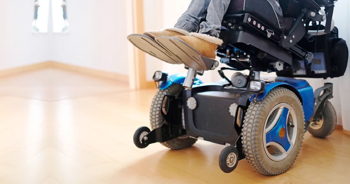 Electric blue power wheelchair carrying seated person with disability.