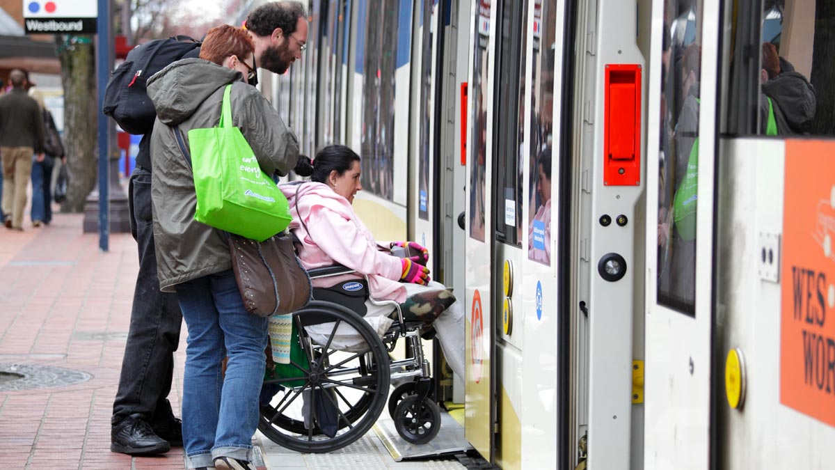 Family boarding train pushing child in a wheelchair at an accessible train station