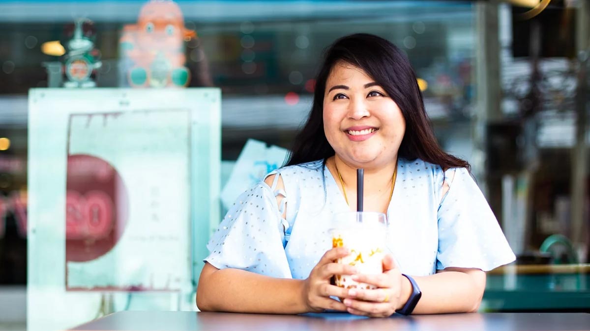 Young Asian woman enjoys a cool drink in a neighborhood coffee shop.