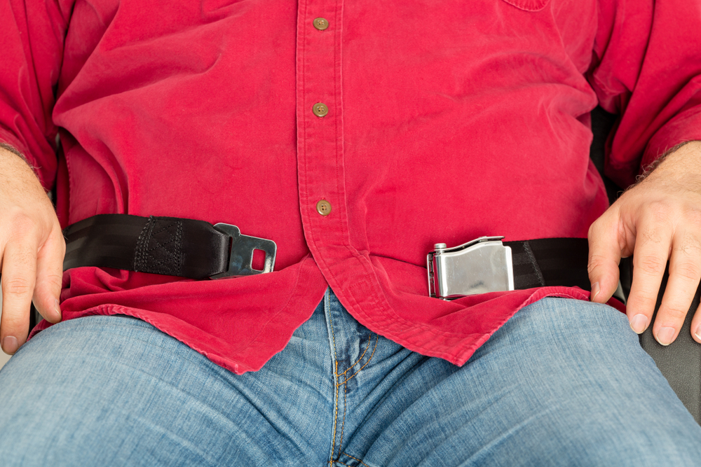 plus-size man is unable to fasten his seatbelt and requires a seatbelt extender.