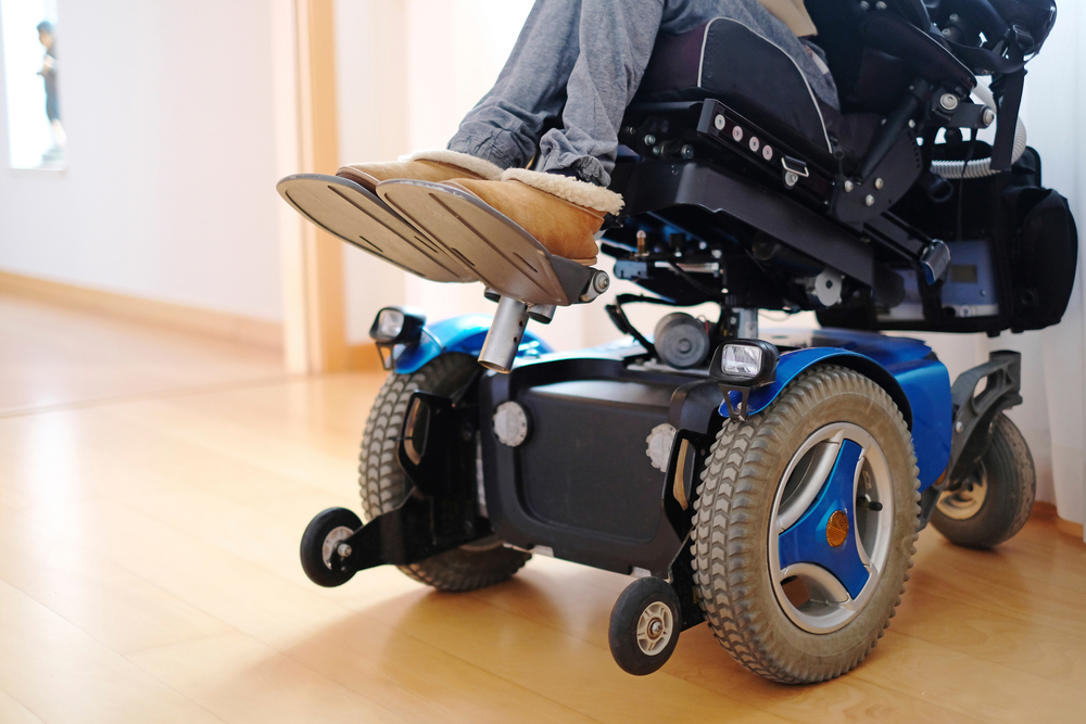 Electric blue power wheelchair carrying seated person with disability.
